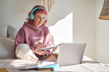 Teen girl sitting on her bed listening to online counsellor