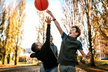 Three boys playing basketball outside