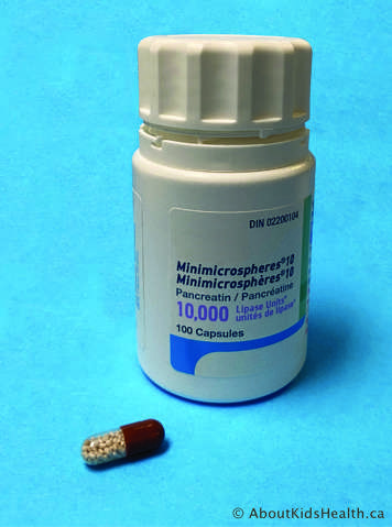 Bottle of cystic fibrosis enzymes with one capsule shown outside the bottle