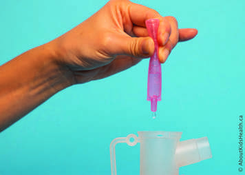 The nebule is squeezed so that medication drips into the nebulizer cup
