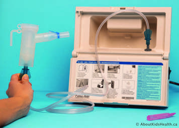 Nebulizer connected to the compressor via tubing and a nebule of medication lying next to the compressor