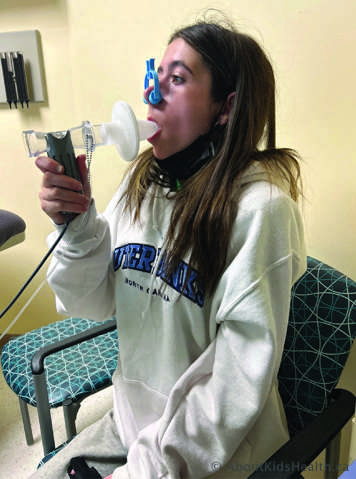 Person with nose clip blowing into a mouthpiece performing spirometry