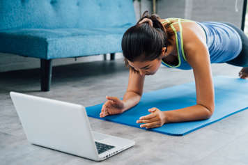 Teen girl in the plank position in front of a laptop