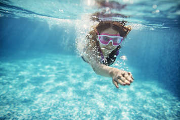 Girl swimming in pool with goggles