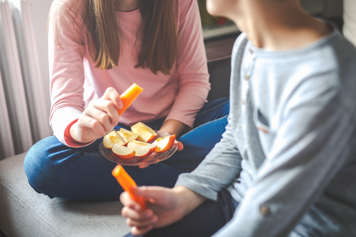 Teen girls eating apples and carrots