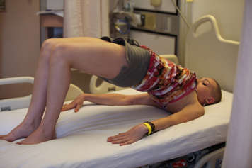 girl laying in hospital bed with hips raised up holding pick me up pose