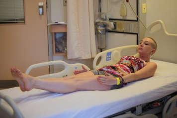 girl laying on hosptial bed with head and feet lifted holding stretch pose