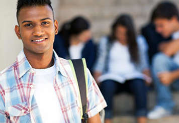 Teen boy wearing backpack with other teens studying in background