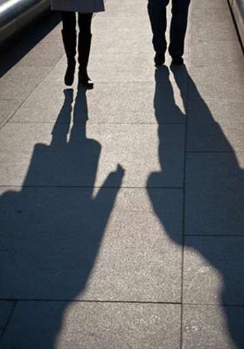 Two people casting a shadow while they walk