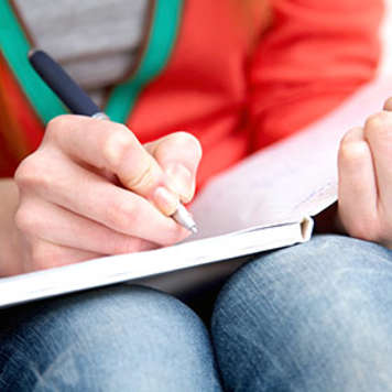 Teen girl writing in notebook