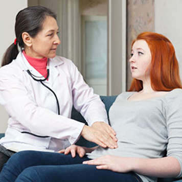 Doctor checking teen girl's abdomen