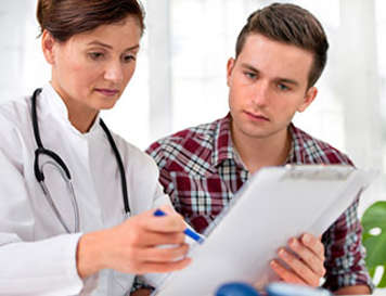 Doctor reviewing medical chart with teen boy