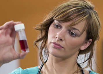 Healthcare professional holding up blood sample in a vial